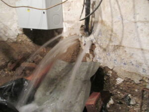 Broken water main pours through foundation wall