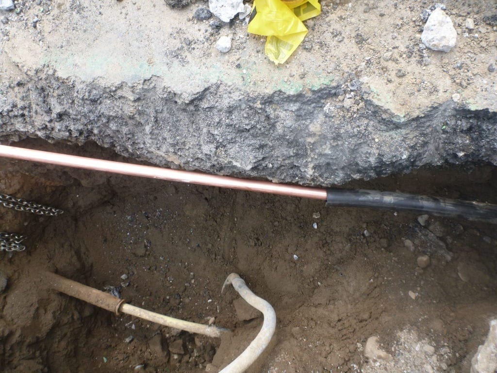 Copper water main installed inside of plastic tubing